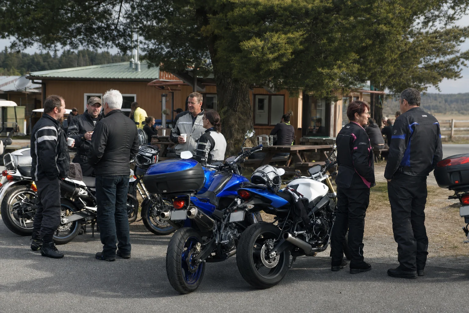 Motorcycle riders talking beside their bikes at a roadside cafe